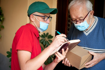 the elderly person receives a package from the postman