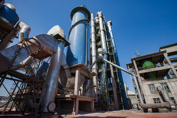 Mynaral, Kazakhstan: Modern Jambyl Cement plant. Silo, tubes and gray factory building on the blue sky background. Panorama view with wide-angle lens.
