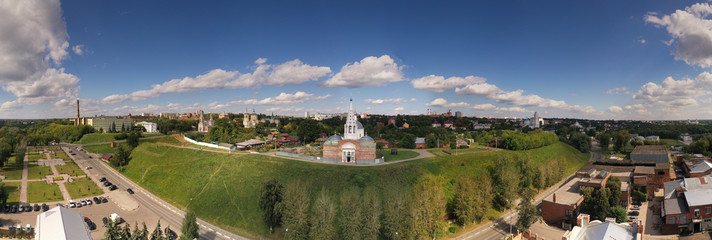 panoramic view of an old church in summer on a green hill against a cloudy sky background