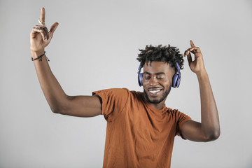 Smiling african-american man in headphones listening to music and dancing