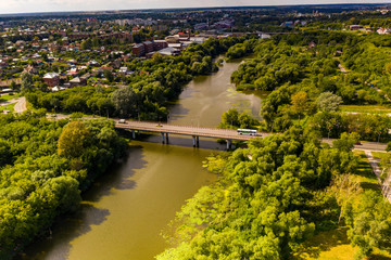 a panoramic view from a drone of a dark river and green trees around in summer
