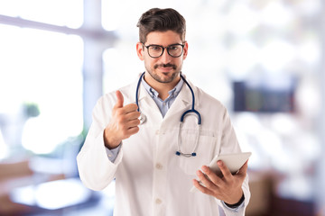 Male doctor giving thumbs up while standing in the hospital