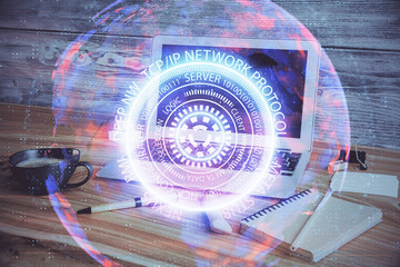 Computer on desktop in office with technology theme hologram. Double exposure. Tech concept.