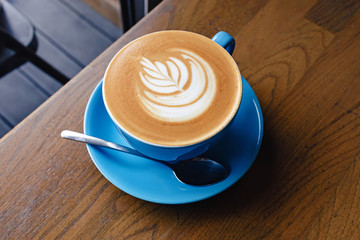 Cup of fresh cappuccino with latte art on the wooden table