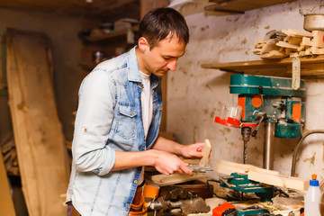 Satisfied cheerful joyful smiling woodmaster is standing near desktop in his workshop, workstation