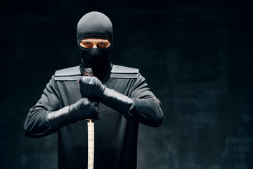 Fighting ninja posing with a sword over black background