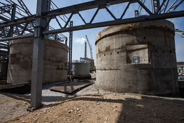 Phosphate fertilizers plant. Grey round concrete construction, mobile crane and plant chimney on...