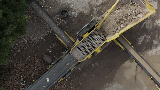 Aerial ascending and rotating top down shot of construction waste sorter machine on sunny day