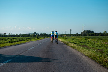 Three professional cyclists ride racing bikes through the fields where the beans are planted. The road is not loaded with cars for us either.