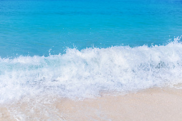 bright turquoise sea with white foam of waves near the sandy shore