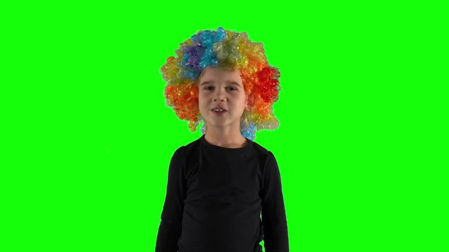 Funny child girl with clown wig simper play act looking at camera