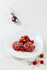 Raspberry and aquafaba ice cream with pistachios on a white plate. Sugar, lactose, gluten free.