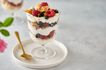 Dessert in a glass with raspberries and blueberries and cream.