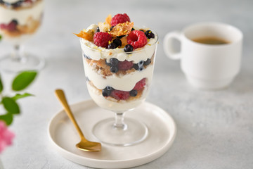 Dessert in a glass with raspberries and blueberries and cream.