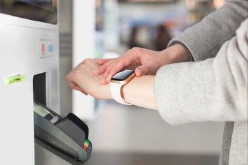 Woman paying at cafe with smart watch wirelessly on easy POS terminal