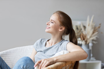 Relaxed young woman on cozy chair with eyes shut closed. Enjoying at home.