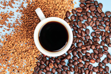 Coffee beans half with instant coffee, in the middle a cup of coffee on a blue background