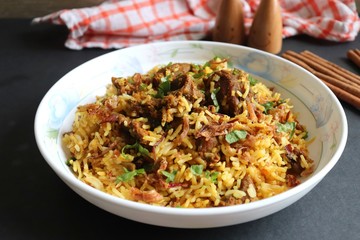 Mutton Biryani or Lamb Pulao. Garnished with fried onion & chopped coriander. Biryani is a famous Spicy non vegetarian dish of India. Goat meat cooked along with Basmati rice & spices. 