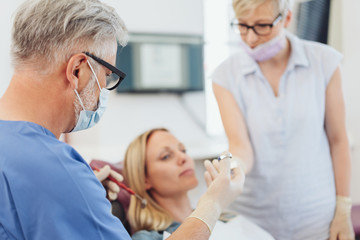 Obraz premium Dentist and nurse handing each other dental tools