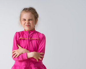 Little girl standing with hands crossed on chest showing grimace on face feeling disgusted with bad...