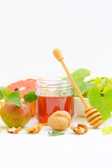 Honey, apples, walnuts, grapefruit and grapes on white wooden background