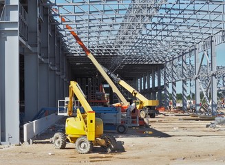 Work aerial platforms at work under a large frame for a new building under construction.