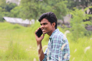 Happy smiling young asian man talking on mobile phone outdoor