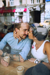 Cute couple flirting in cafe behind the window