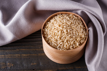 raw brown rice on dark rustic wooden background