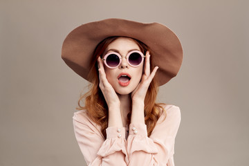  red-haired woman in hat and shirt on beige background makeup smile charm youth fashion