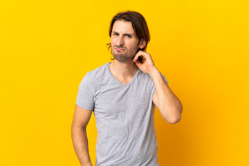 Young handsome man isolated on yellow background having doubts