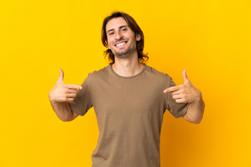 Young handsome man isolated on yellow background proud and self-satisfied