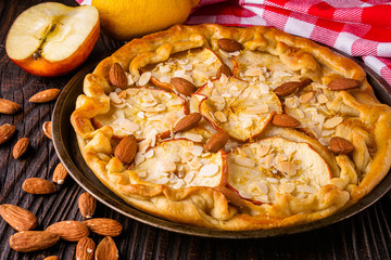crispy apple galette with almonds on rustic wooden background