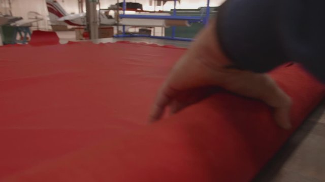 Worker repacking red leather roll, slowmotion