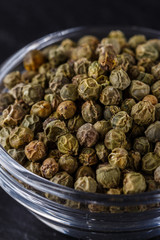 green peppercorns on dark slate stone background