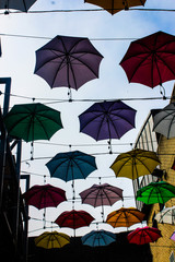 Fototapeta na wymiar Umbrellas outside Zozimus Bar in Anne's Lane ( suspended across laneway at roof height)various colours at roof height