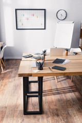 Stationery, digital devices and coffee to go on wooden tables in white office