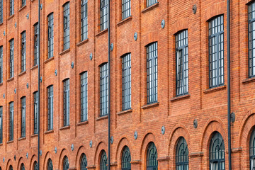 Red brick classic industrial building facade with multiple windows background.
