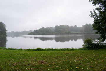 misty lake in the early morning with green trees