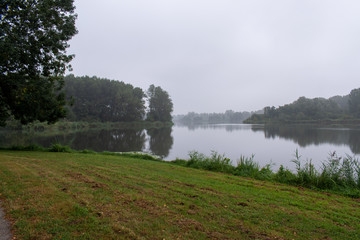 misty lake in the early morning with green trees