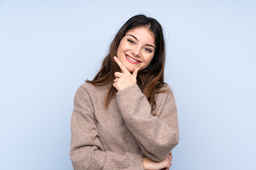 Young brunette woman wearing a sweater over isolated blue background smiling
