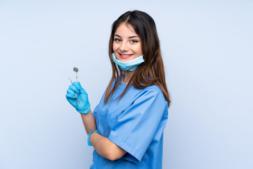 Woman dentist holding tools over isolated blue background laughing