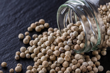 white peppercorns on dark slate stone background