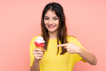 Young brunette woman holding a cornet ice cream over isolated pink background with surprise facial expression