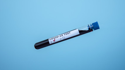Test tube with blood sample for COVID-19, isolated on blue background. Coronavirus test. Positive...