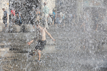 Junge badet bei Hitzewelle im Springbrunnen am Karlsplatz in München