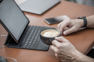 man holding a cup of coffee and working on notebook from home