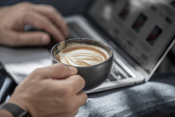 man holding a cup of coffee and working on notebook from home