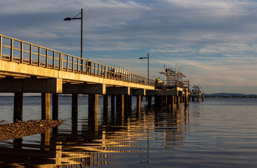 Jetty in golden light with reflections in water