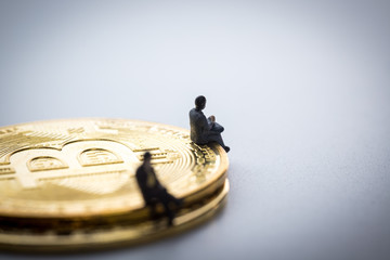 The miniture business man sitting on the bitcoins on white background